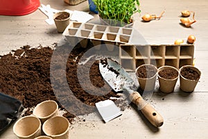 Garden tools with fertile black soil with shovel and cardboard pot for seeds. Spring planting time