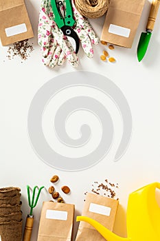 Garden tools on a white background. Frame of peat pots, paper bags with seeds, watering can, gloves, garden shears