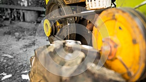 Garden walk-behind tractor close-up on a black and white background. Yellow pulley with belt drive for torque transmission. Wheel