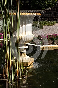 Garden water fountain in pond with reeds