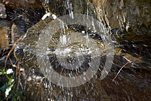 Garden waterfall of stones. Water flows through the stone. The morning sun shines on the waterfall.