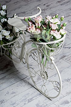 Garden white bicycle with a a basket of flowers roses