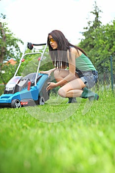 Garden work, woman mowing grass with lawnmower