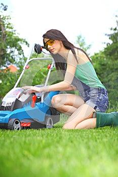 Garden work, woman mowing grass with lawnmower