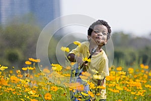 In the garden, a young African boy can be seen joyfully playing with a watering device.