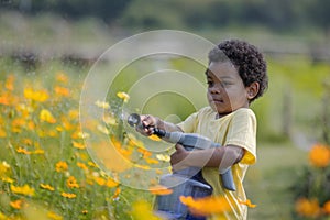 In the garden, a young African boy can be seen joyfully playing with a watering device.