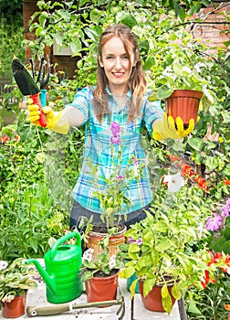 Gardener active happy girl is holding the pot of flower and gardening tools.