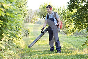 Gardener clearing up the leaves using a leaf blower