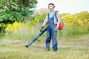Gardener clearing up the leaves using a leaf blower