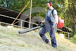 Gardener clearing up the leaves using a leaf blower