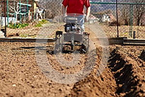 Gardener cultivate ground soil with tiller tractor or rototiller, cutivator