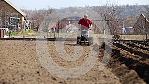 Gardener cultivate ground soil with tiller tractor or rototiller, cutivator