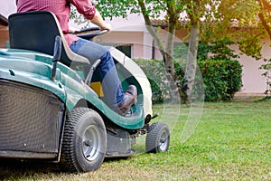 Gardener cutting the grass of a gardenon a lawn mower