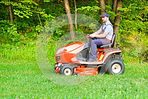 Gardener driving a riding lawn mower in garden