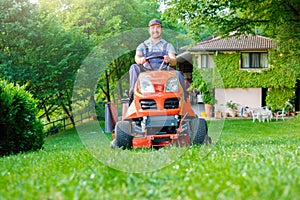 Gardener driving a riding lawn mower in garden