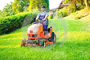 Gardener driving a riding lawn mower in garden