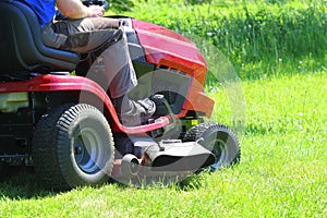 Gardener driving a riding lawn mower in a garden photo