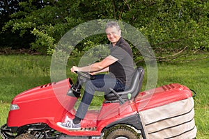 Gardener driving riding lawn mower in garden