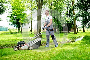 Gardener equipped with lawnmower on the job photo