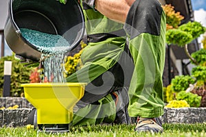 Gardener Filling His Handheld Spreader with Granular Lawn Fertilizer