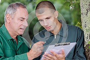 gardener holding clipboard training apprentice