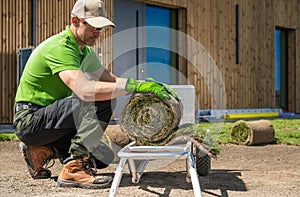 Gardener installing grass turfs inside a backyard garden