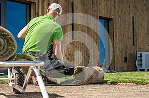 Gardener installing new grass turfs in front of a house