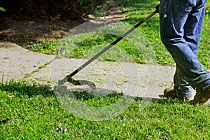 The gardener man mows the grass with a hand lawn mower
