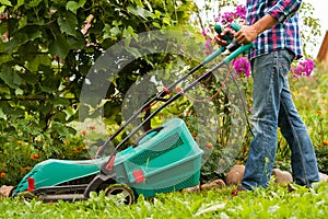 Gardener Mow Grass With Lawn Mower In Garden.