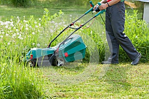 Gardener Mow Grass With Lawn Mower In Garden. photo