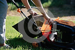 Gardener mows the lawn in the garden with a lawn mower in summer