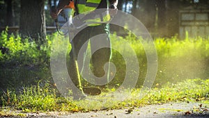 The gardener mows weeds. small parts of vegetation scatter in different directions