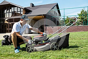 The gardener prepares the lawn mower to start the engine.