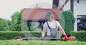 Gardener in protective mask and clothes pruning bushes