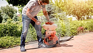 Gardener in protective mask and glasses spraying toxic pesticides trees