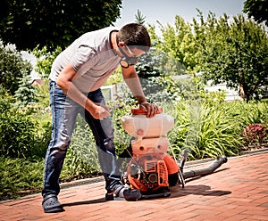 Gardener in protective mask and glasses spraying toxic pesticides trees