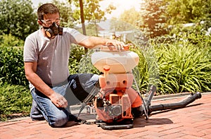 Gardener in protective mask and glasses spraying toxic pesticides trees