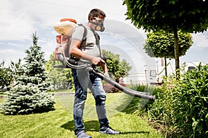 Gardener in protective mask and glasses spraying toxic pesticides trees