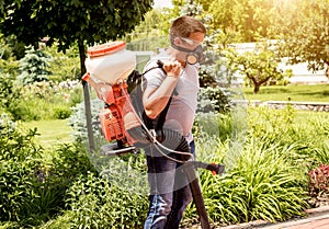 Gardener in protective mask and glasses spraying toxic pesticides trees