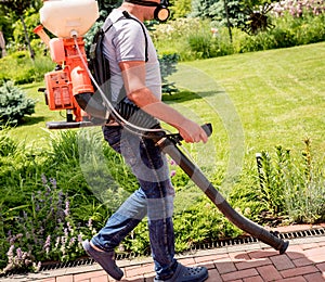 Gardener in protective mask and glasses spraying toxic pesticides trees