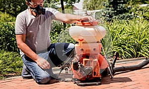 Gardener in protective mask and glasses spraying toxic pesticides trees