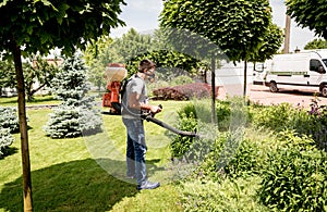 Gardener in protective mask and glasses spraying toxic pesticides trees