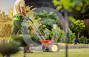 Gardener with Push Spreader Fertilizing Residential Grass Lawn