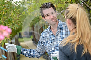 Gardener showing flowers to woman