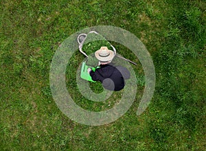the gardener in the straw hat dumped the mower's basket into