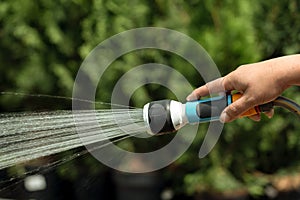 Gardener watering plants using hose in a garden shop