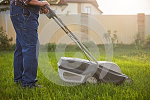 Gardener wearing jeans and mowing a lawn