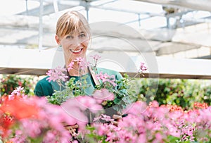 Gardener woman in her greenhouse with flowers for sale