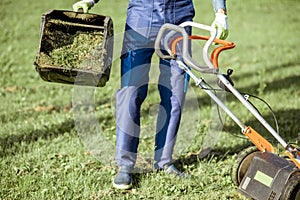 Gardener working with lawn mower on the backyard