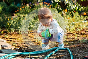Gardening and harvesting. A cute baby girl is playing with a plastic toy bucket in the backyard. Outdoor